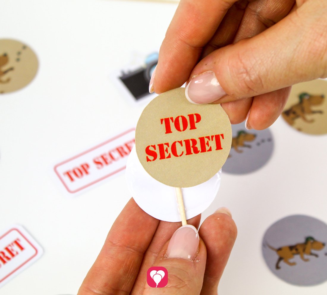 Für einen balloonas Detektiv Deko Picker, beispielsweise mit der Aufschrift TOP SECRET, werden die Vorder- und Rückseite der einzelnen Mottos auf einem Zahnstocher zusammengeklebt.