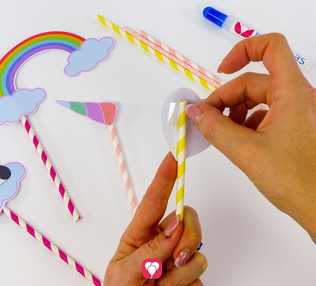 Im nächsten Schritt wir das ausgeschnittene Herz-Motiv an einen Strohhalm geklebt. So entsteht mit der Bastelvorlage von balloonas eine Requisite für ein Photo Booth.